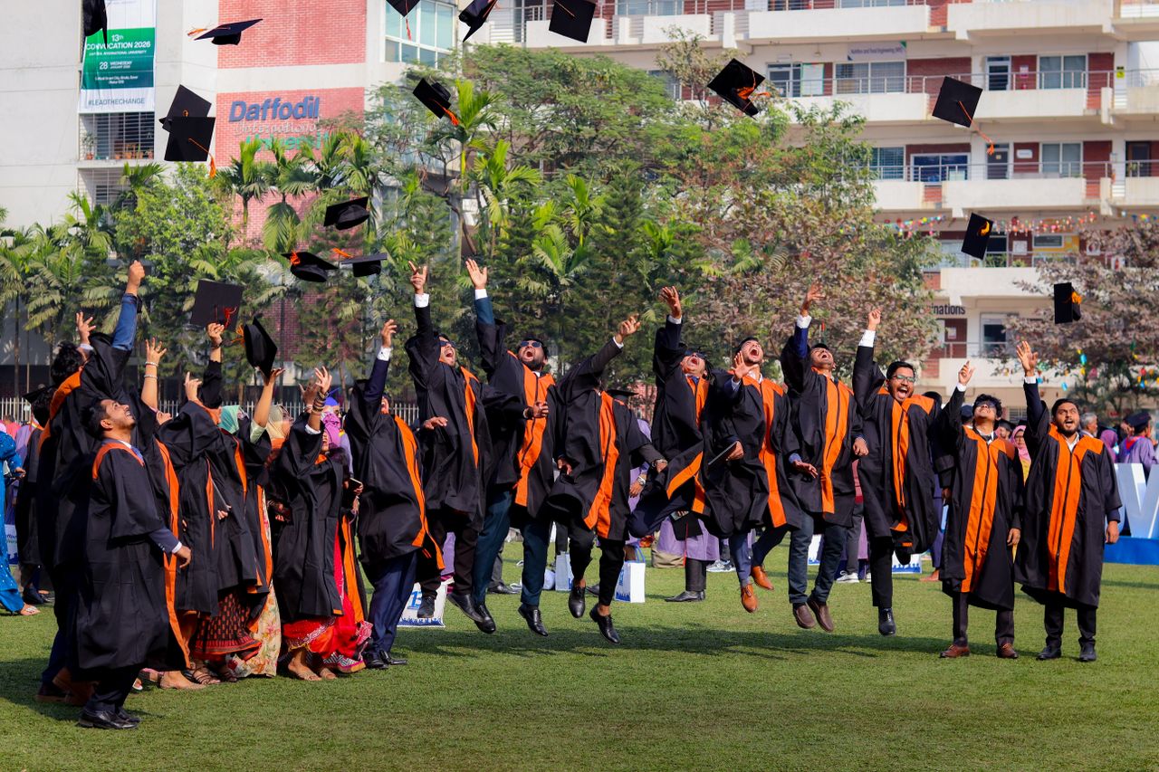 Services Graduates joyfully toss caps in the air during outdoor ceremony, celebrating graduation day.