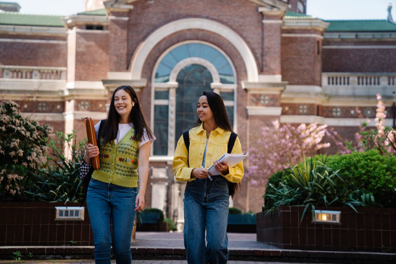 Mastering the First Impression: Your intriguing post title goes here Two smiling young women walk together on a beautiful college campus.